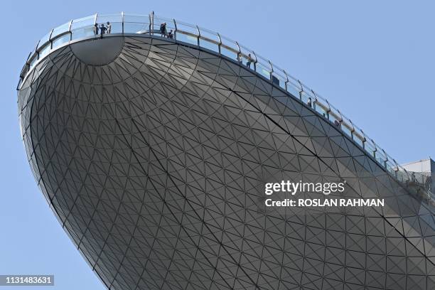 People look out from the observation deck of the Sands SkyPark at the Marina Bays Sands hotel and resort in Singapore on March 19, 2019. - Paris has...