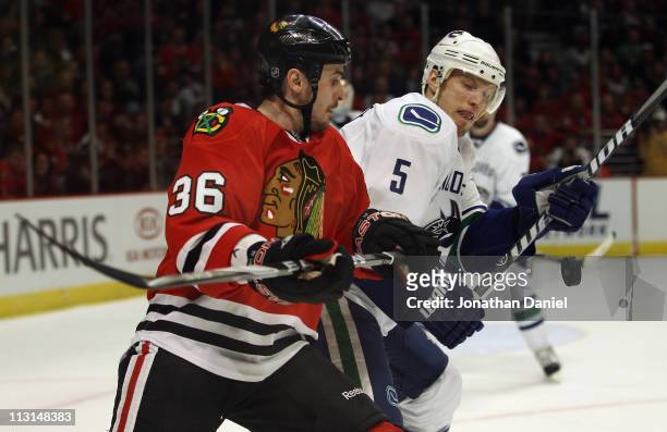 Dave Bolland and Christian Ehrhoff of the Chicago Blackhawks of the Vancouver Canucks battle for the puck in Game Six of the Western Conference...