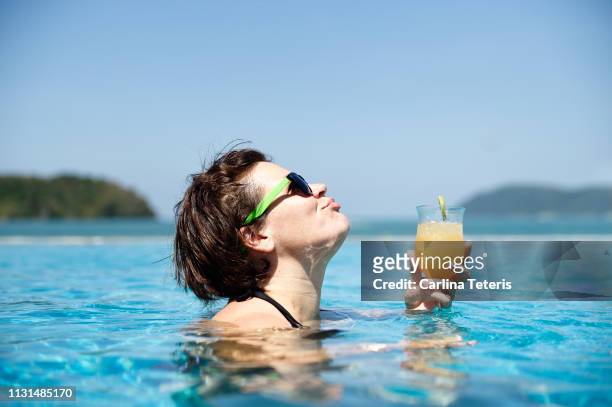 woman laughing in a resort pool with a cocktail - tropischer cocktail stock-fotos und bilder