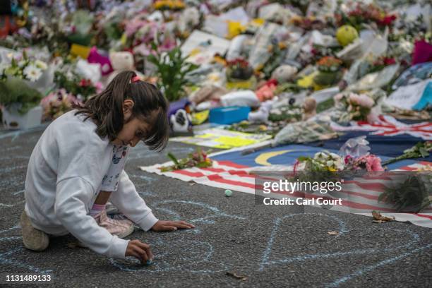 Young girl writes a message on the ground with chalk next to flowers and tributes near Al Noor mosque on March 19, 2019 in Christchurch, New Zealand....
