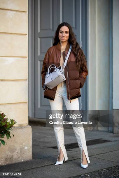 Erika Boldrin, wearing brown puffer jacket, pants with slit and white bag, is seen outside Tod's on Day 3 Milan Fashion Week Autumn/Winter 2019/20 on...