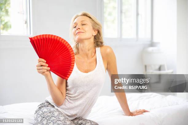 woman cooling down with a fan. - hot flash stock pictures, royalty-free photos & images