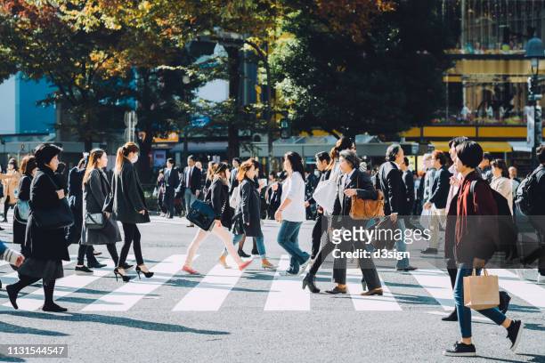 crowd of busy commuters crossing street in shibuya crossroad, tokyo - beengt stock-fotos und bilder