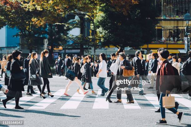 crowd of busy commuters crossing street in shibuya crossroad, tokyo - attraversamento pedonale foto e immagini stock