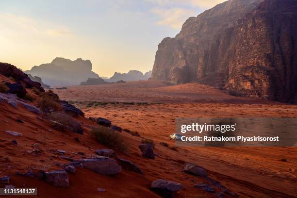 sunrise scene of red sand dune and amazing rock in wadi rum desert, jordan - car cinema fotografías e imágenes de stock