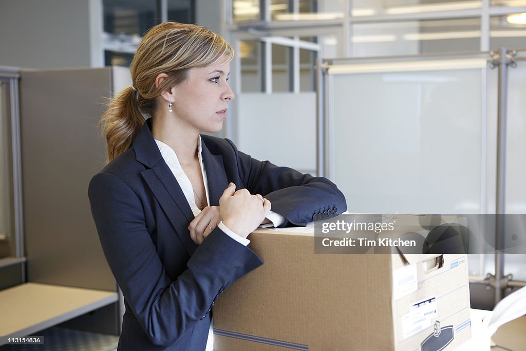 Woman with moving boxes in office, thinking