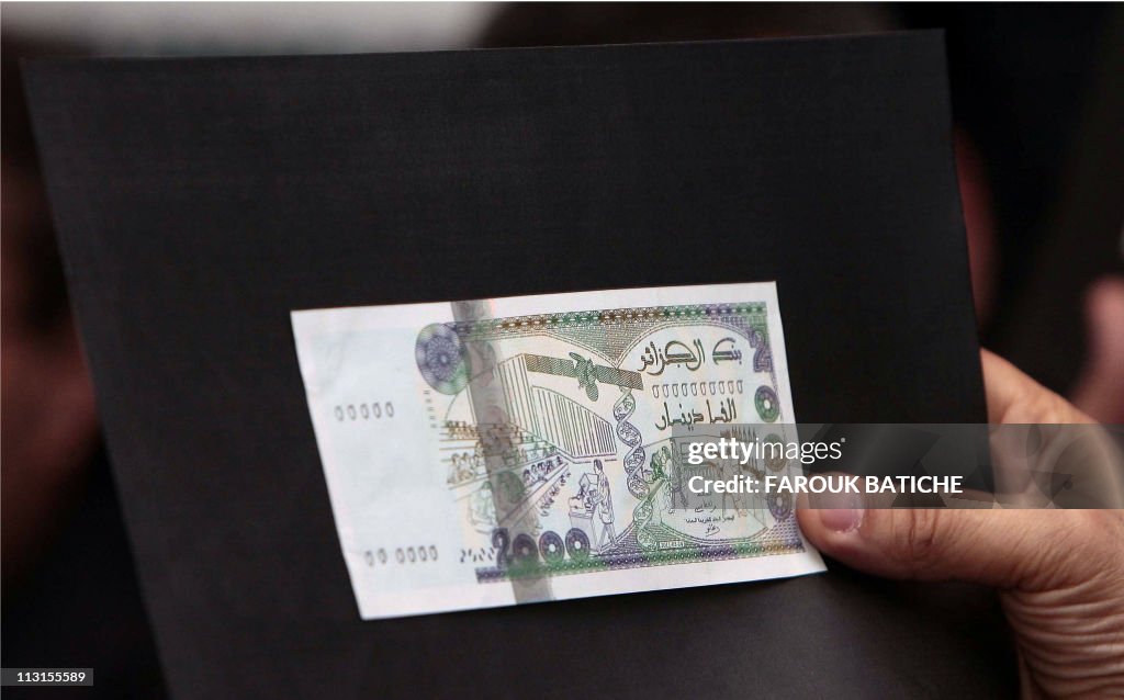 A man shows a 2000 dinars banknote (20 e