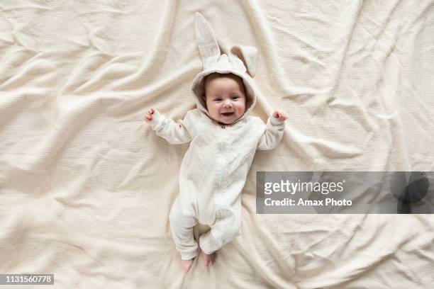 自宅で毛布の上にバニーの衣装でかわいい赤ちゃん、トップビュー - easter rabbit ストックフォトと画像