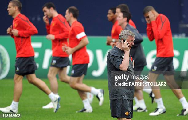 Manchester United manager Alex Ferguson speaks on the phone during a training session on April 25, 2011 in Gelsenkirchen, western Germany. German...