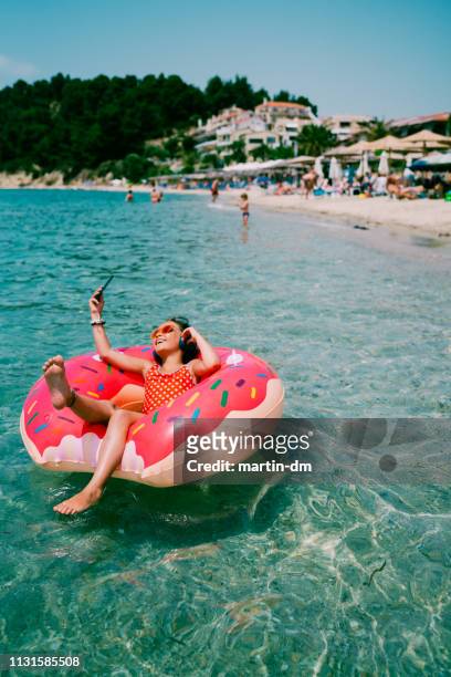 kind schwimmt auf wasser in donut leben gürtel - girls sunbathing stock-fotos und bilder