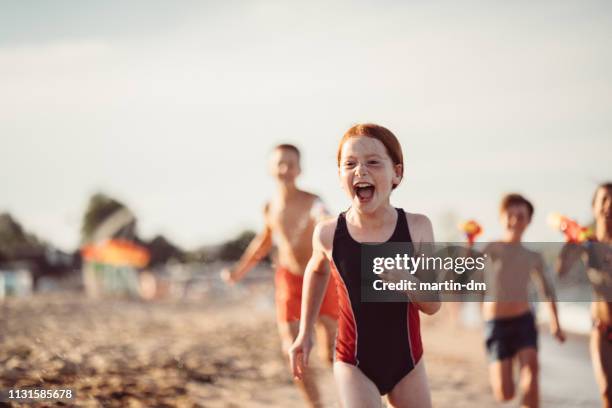 kinder laufen und schießen mit wasserpistole am strand - young girl swimsuit stock-fotos und bilder