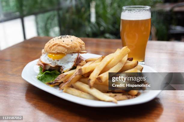 close up of delicious burger with egg, bacon, fries and beer - bacon imagens e fotografias de stock