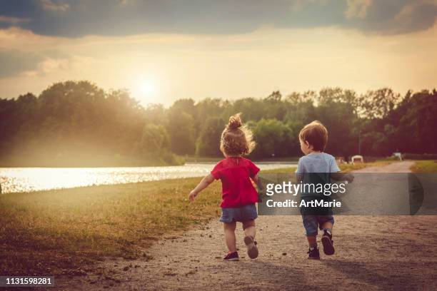 cute boy and girl outdoors playing outdoors in summer sunset - boys running stock pictures, royalty-free photos & images