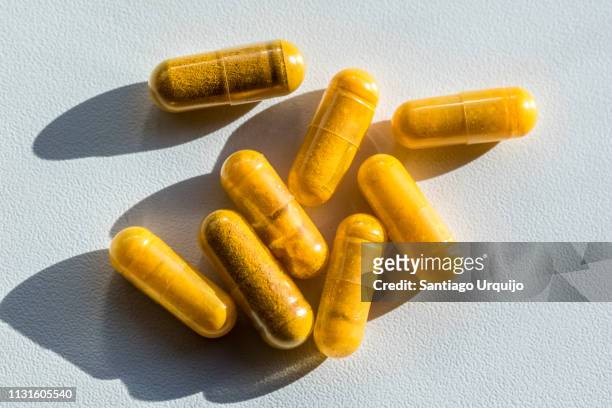 close-up of turmeric capsules on table - tumeric stock pictures, royalty-free photos & images