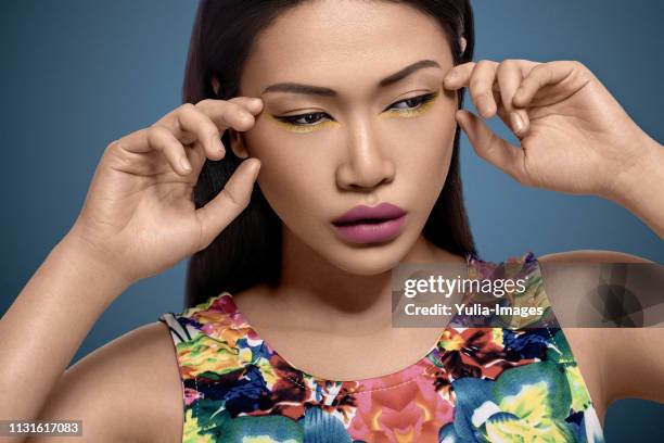 close-up of beautiful woman touching face against blue background - eye liner 個照片及圖片檔