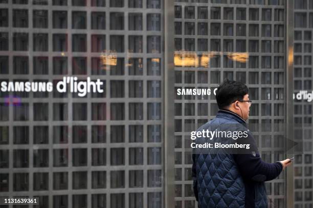 Man walks past Samsung Electronics Co. Logos displayed outside the company's Seocho office building in Seoul, South Korea, on Wednesday, March 20,...