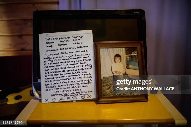 This photo taken on March 19, 2019 in Lyttelton, close to Christchurch, shows a photo of Sayyad Milne as a young boy and a whiteboard with a letter...