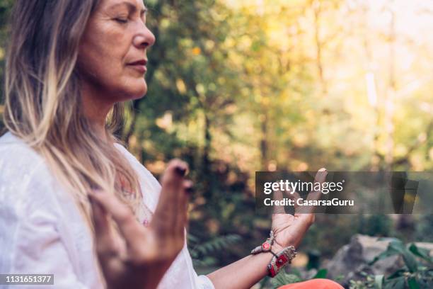 mature woman meditating in forest - wilderness stock pictures, royalty-free photos & images