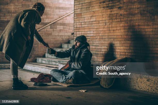 vrouw geld te geven aan bedelaar - homelessness stockfoto's en -beelden