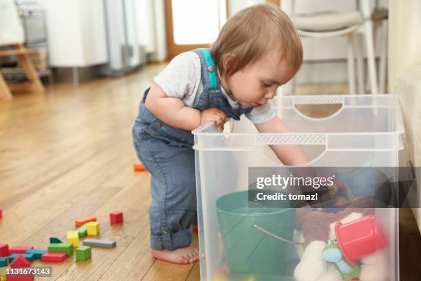 kleiner junge, der seine kiste mit spielzeug untersucht - toy box stock-fotos und bilder