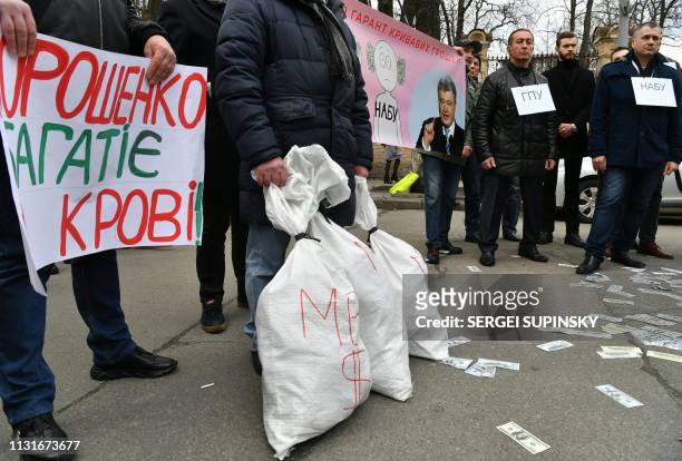 An activist of the "Movement of New Forces" party, founded by former Georgian President, holds a sign reading "Poroshenko gets rich in blood !" as...