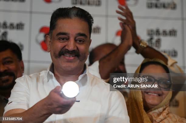 Indian cinema actor and founder of 'Makkal Needhi Mayyam' party Kamal Hassan gestures as he holds the party symbol, a torchlight, during the...