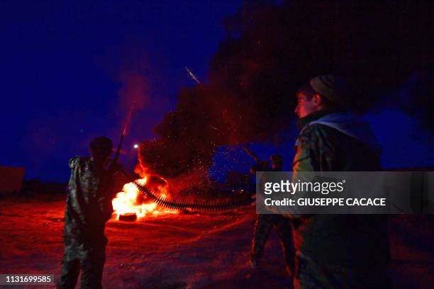 Fighter with the Kurdish-led Syrian Democratic Forces fire shots in the air as they stand around a bonfireduring Nowruz celebrations near the village...