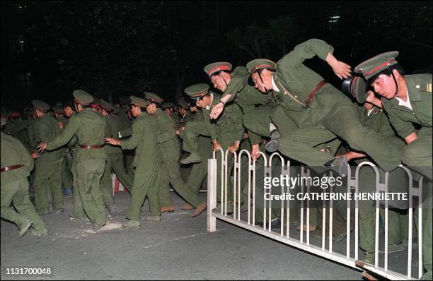 People Liberation Army soldiers leap over a barrier on Tiananmen Square in central Beijing 04 June 1989 during heavy clashes with people and...