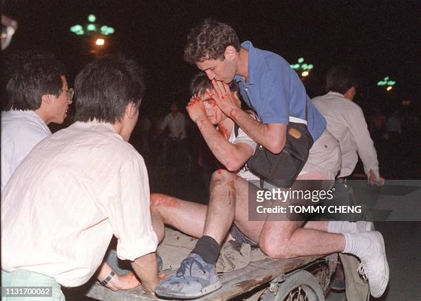 Taken care by others, an unidentified foreign journalist is carried out from the clash site between the army and students 04 June 1989 near Tiananmen...