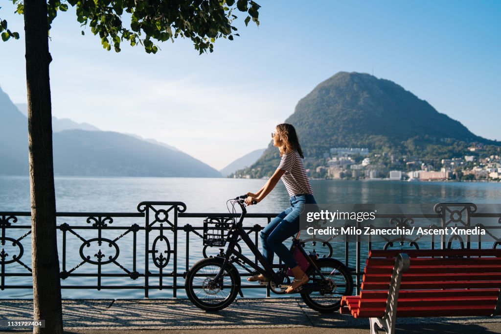 Woman enjoys lake promenade with bicycle