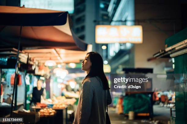 young asian woman exploring and strolling in local street market in hong kong at night - travel market asia stock-fotos und bilder
