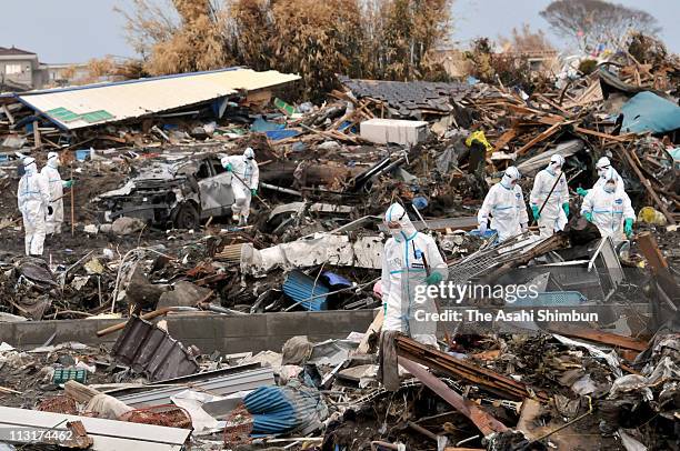 Police officers wearing radiation protective clothing continue search for bodies of the earthquake and tsunami vicitms amongst rubble 7km from the...