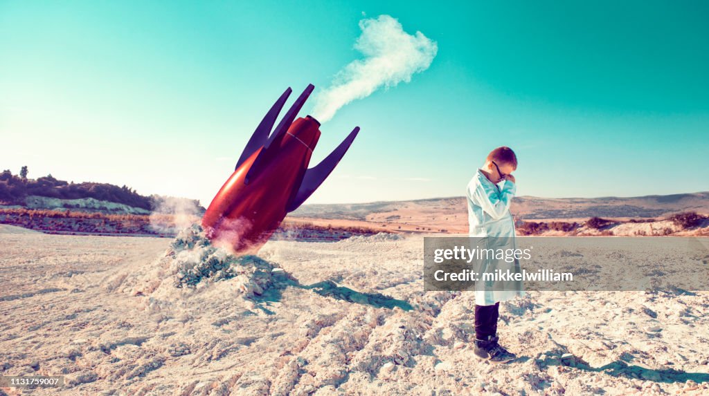 Rocket fails and falls to the ground while child in lab coat shows his disbelief