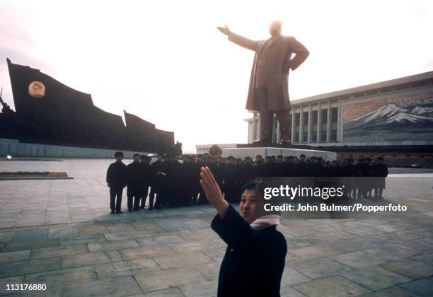 Guide with a group of visitors to the Mansudae Grand Monument , which depicts the North Korean revolutionary struggle, Pyongyang, North Korea,...