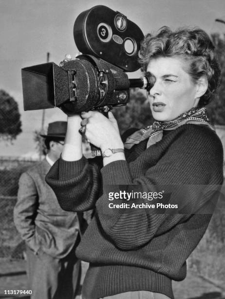 Swedish actress Ingrid Bergman using a film camera on set of the movie 'We, the Women' in 1953.