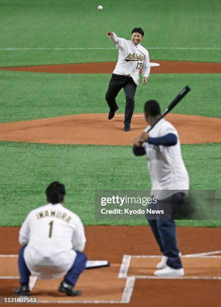 Former Oakland Athletics pitcher Keiichi Yabu throws the ceremonial first pitch to former Seattle Mariners outfielder Ken Griffey Jr. Before the...