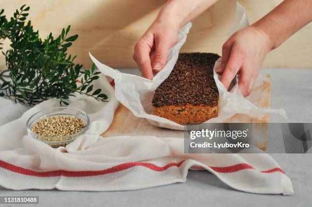 homemade vegan bread on a leaven of green buckwheat with flax seeds, sunflower in women's hands on a wooden background. healthy and proper nutrition. - buchweizen stock-fotos und bilder