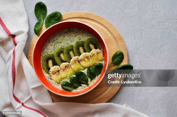 bright plate with a healthy breakfast power bowl made of natural yogurt, chia seeds, banana, kiwi, celery and spinach on a gray background. top view. copyspace - nut butter stock pictures, royalty-free photos & images