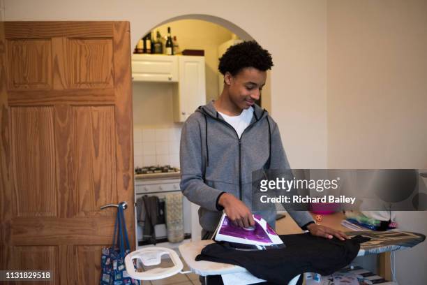 mixed race teenager ironing a shirt with his mum. - ironing stock pictures, royalty-free photos & images