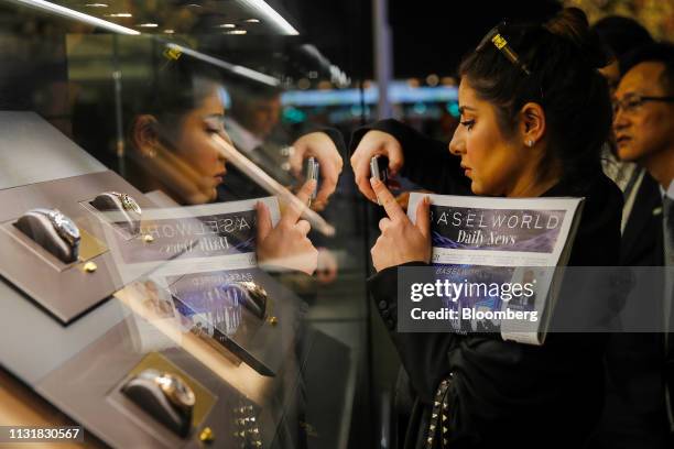 Visitor takes a smartphone photograph of luxury wristwatches on display during day two of the 2019 Baselworld luxury watch and jewellery fair in...