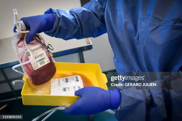 Lab tech handles a blood bag after it passed through a laboratory centrifuge before genetically modifying a patients immune cells on March 8, 2019 at...