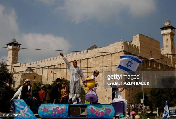 Israeli settlers celebrate the Jewish Purim holiday in front of Ibrahimi Mosque at al-Shuhada street in the divided West Bank town of Hebron, on...