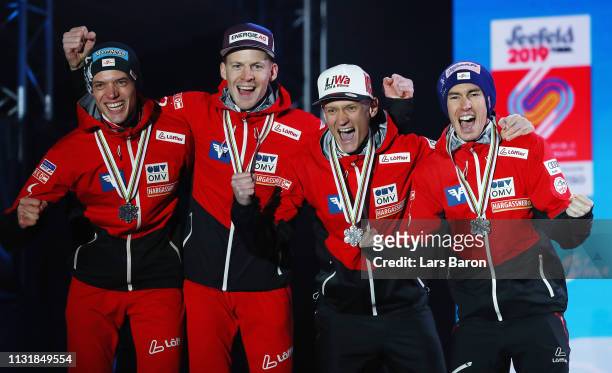 Silver medalists Philipp Aschenwald, Michael Haybock, Stefan Kraft and Daniel Huber of Austria celebrate during the medal ceremony for the Men's Team...