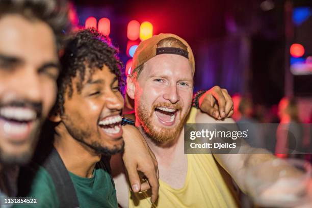 three happy young men partying at music festival at night. - selfie three people stock pictures, royalty-free photos & images