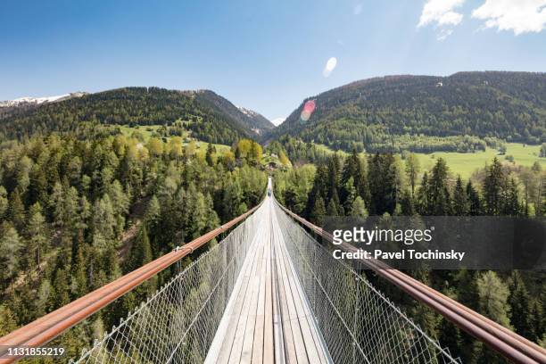 suspension bridge over young rhone river near ernen, valais, switzerland, known as 'goms bridge', 2018 - sterk perspectief stockfoto's en -beelden