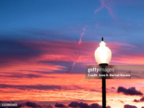 red sky in the sunset with a lamppost ignited with a bulb of low consumption led. - led street lighting stockfoto's en -beelden