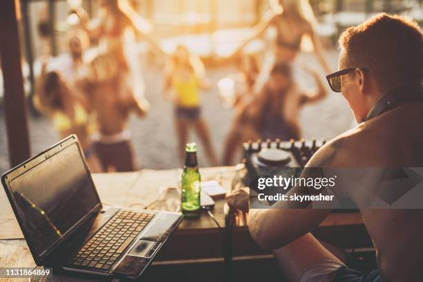 rear view of a dj playing music on the beach party. - record player stock pictures, royalty-free photos & images