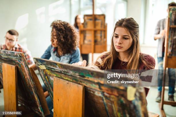 grupo de estudantes que fazem suas pinturas em uma classe no estúdio de arte. - desenhar atividade - fotografias e filmes do acervo