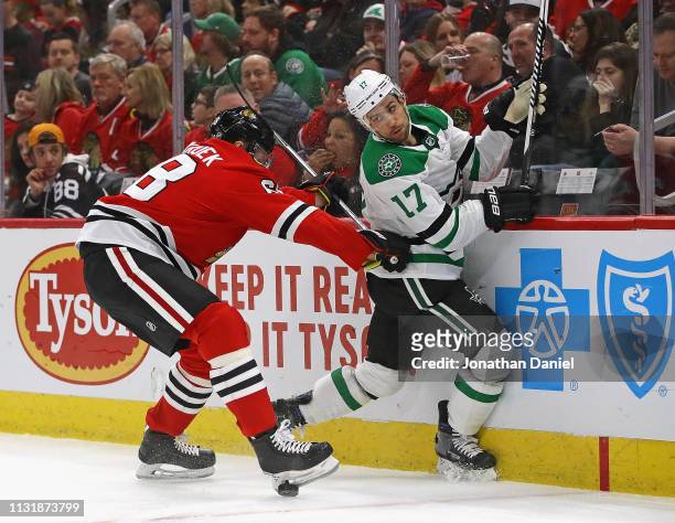 Slater Koekkoek of the Chicago Blackhawks hits Andrew Cogliano of the Dallas Stars in the back with his stick while battling along the boards for the...