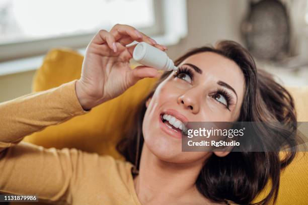 happy woman taking eye drops - eyedropper stock pictures, royalty-free photos & images